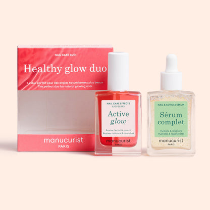 A pink and white box labeled Healthy Glow Duo by Manucurist sits next to two Manucurist bottles: a red nail polish, Active Glow, and a clear nail serum, Sérum Complet.