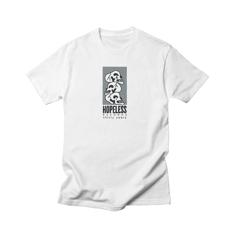 A white Comfort Colors t-shirt from Hopeless Records featuring a modern black and white graphic of three dinosaur skulls stacked above HOPELESS thirty years. Minimalist design—ideal for unique apparel enthusiasts.