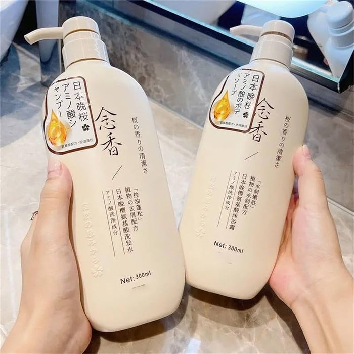 Two beige 300ml bottles of Japanese amino acid shampoo and body soap with pump dispensers held over a marble counter