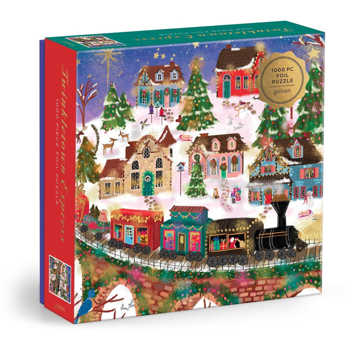 Box of the Joy Laforme Twinkletown Express 1,000 Piece Jigsaw Puzzle by Chronicle Books, featuring a vibrant holiday village scene with decorated houses, Christmas trees, and the festive Twinkletown Express train traveling through a snowy landscape.