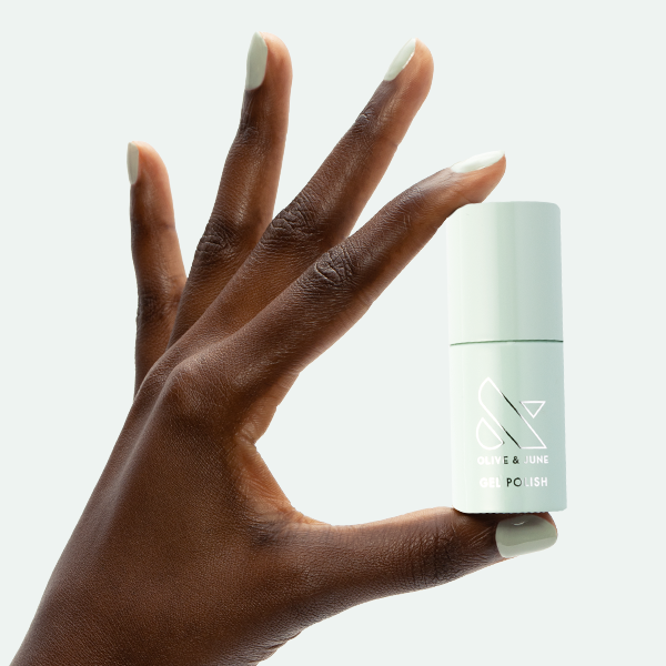 KMC - Gel bottle held by hand with nails painted in a soft neutral shade for a polished gel manicure by Olive and June