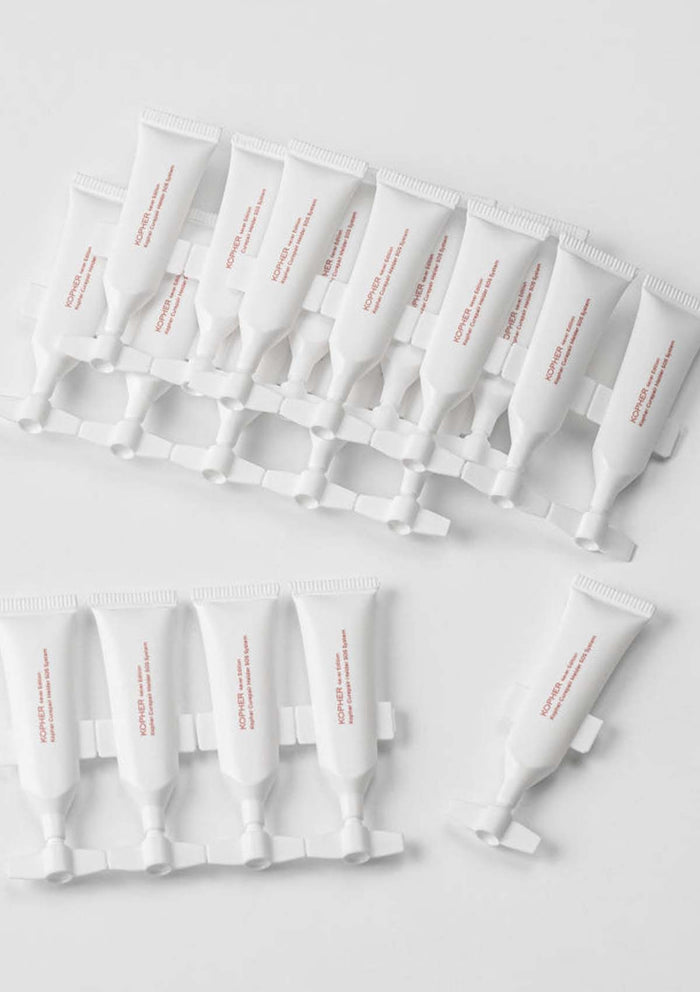 Multiple white skincare tubes with red text on a light gray background