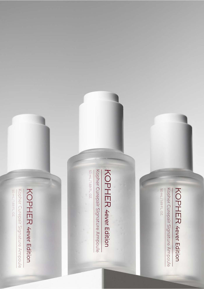 Three Kopher skincare bottles on a gray background