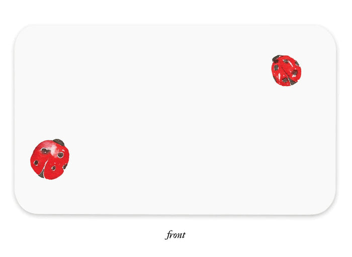 White notebox front with scattered ladybug stickers in red and black, rounded corners