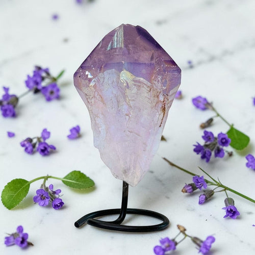 Crystal on a stand with purple flowers on a light background