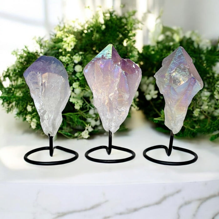 Three crystal rock formations on stands with a blurred greenery background