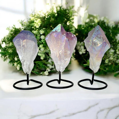 Three crystal rock formations on stands with a blurred greenery background