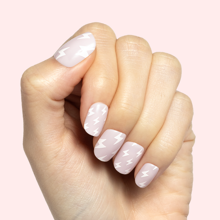 Lightning Strike | Extra Short | Squoval - Tab Press-On neutral false nails with white lightning bolt pattern on hand against pale pink background