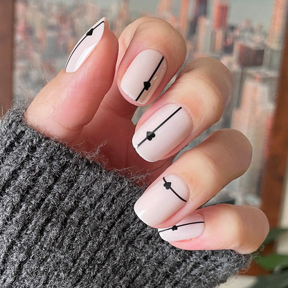 Linear Hearts | Short | Squoval - Tab Press-On neutral nails with thin black lines and tiny heart accents on hand in gray knit sleeve
