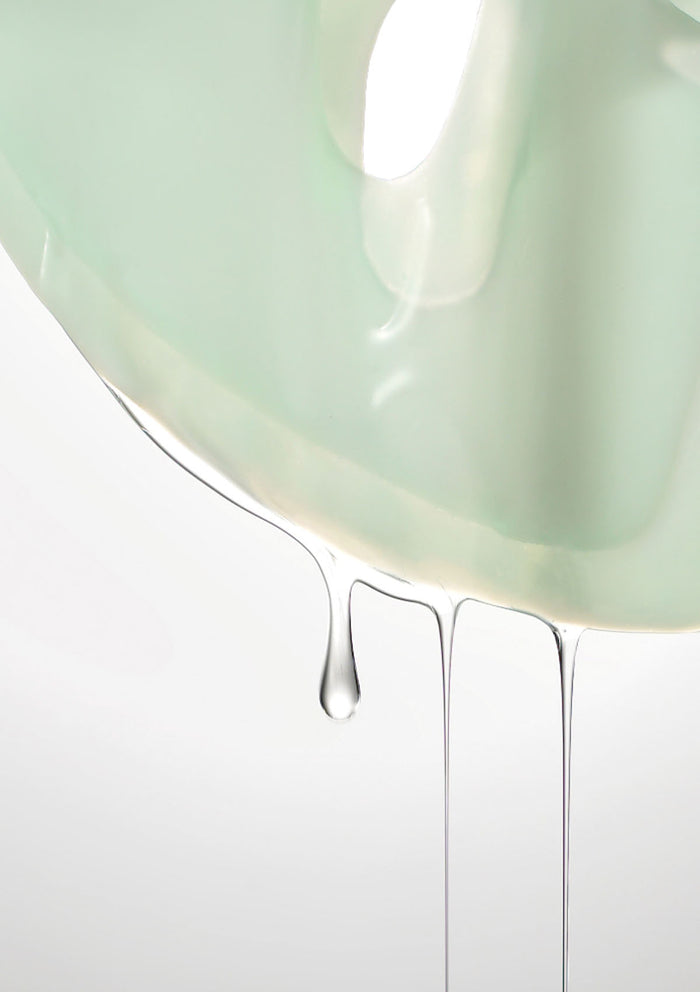 Close-up of a light green ceramic bowl with water droplets on a white background