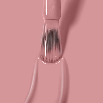 Close-up of a brush applying LONDONTOWN's Mauve Over gel nail polish, with bristles coated in the streak-free color against a pink background.