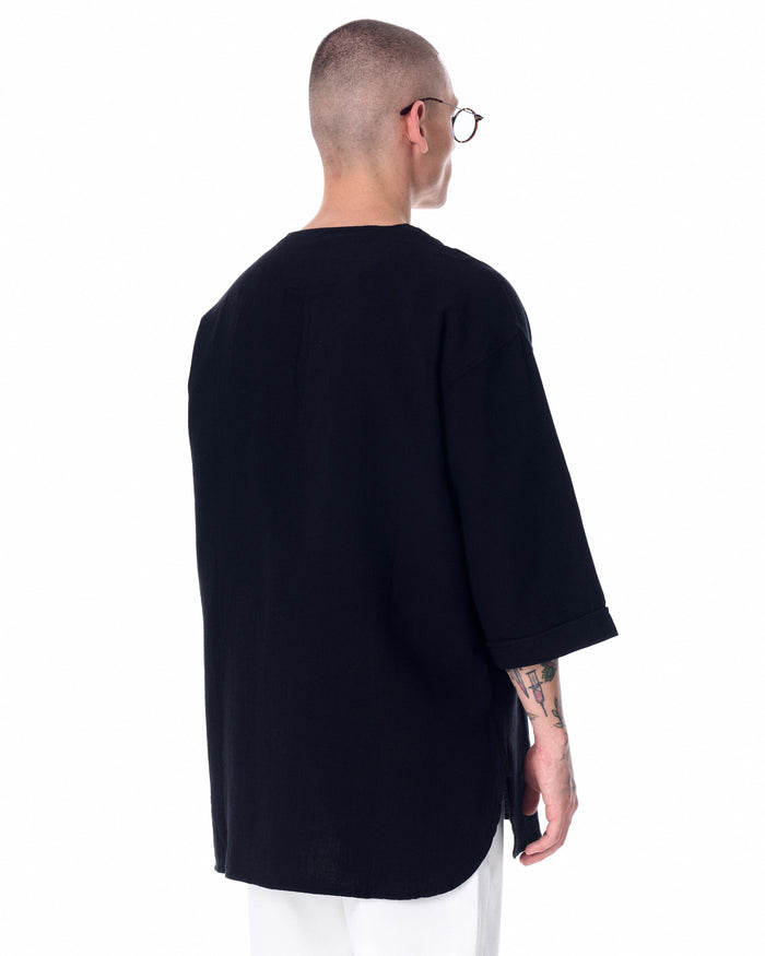Martin Valen oversized black linen men's t‑shirt, left profile view showing dropped shoulder and side split hem