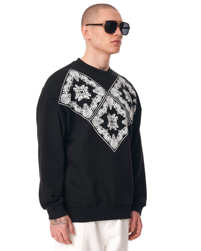 Martin Valen men's oversized black sweatshirt, three-quarter view showing white ethnic V-shaped print across the chest