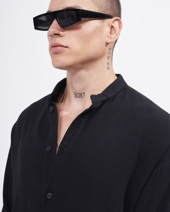 Martin Valen men’s oversized black linen mandarin-collar shirt, oblique close-up on collar and buttons, model wearing a chain