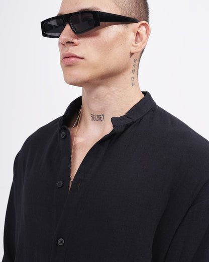Martin Valen men’s oversized black linen mandarin-collar shirt, oblique close-up on collar and buttons, model wearing a chain