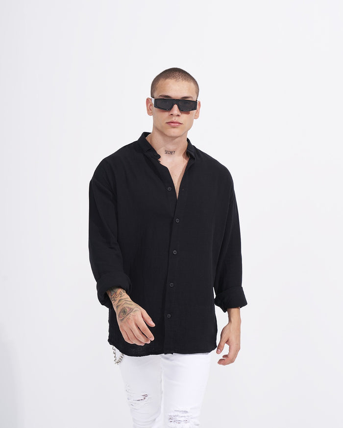 Martin Valen oversized black linen mandarin-collar shirt, three-quarter front view on model wearing black sunglasses