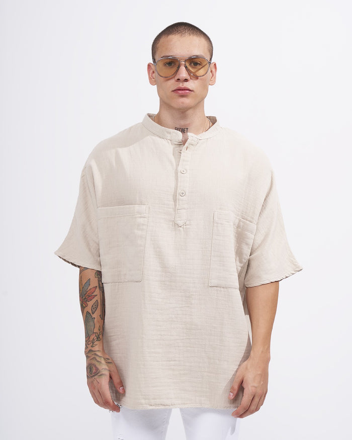 Martin Valen oversized beige linen shirt, front mid-body view with mandarin collar, half-button placket and patch pockets