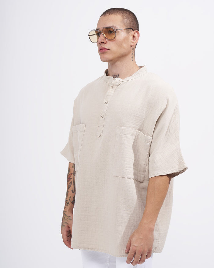 Martin Valen oversized beige linen shirt, slight profile view showing mandarin collar, short wide sleeves and front patch pockets