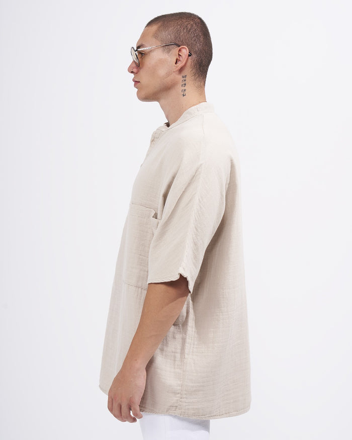 Martin Valen oversized beige linen half-button shirt with mandarin collar, side profile showing chest pocket