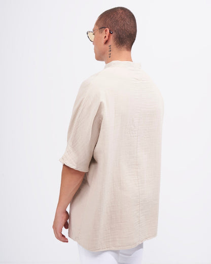 Martin Valen oversized beige linen mandarin-collar shirt, three-quarter back view highlighting the loose fit and short sleeves