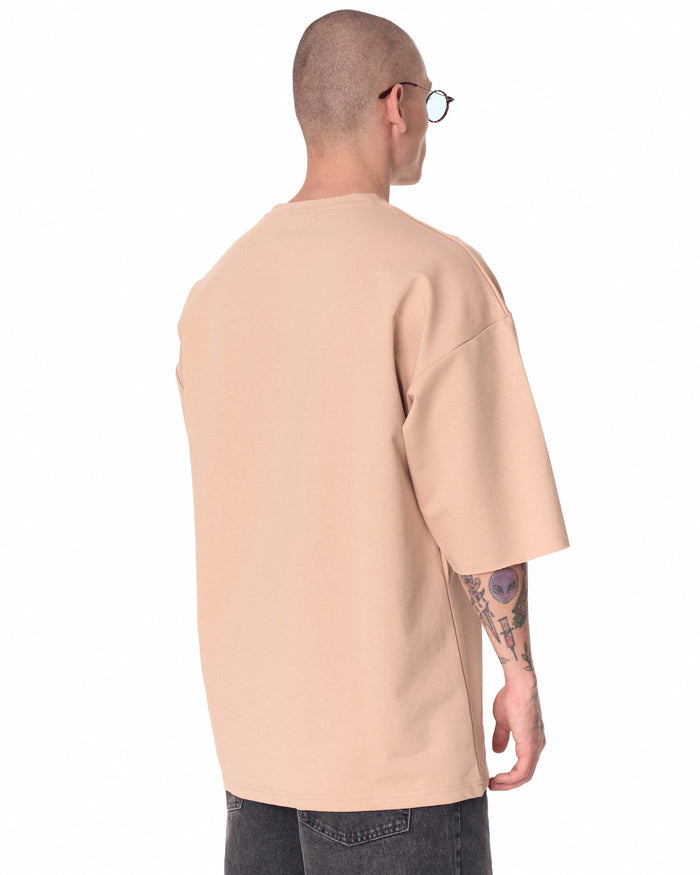 Martin Valen oversized beige T‑shirt in three‑quarter profile, chest logo visible and dropped shoulder sleeve