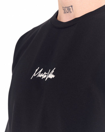 Martin Valen oversized black chest-printed T-shirt, three-quarter view showing chest logo and model profile
