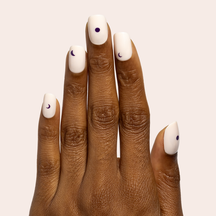Moon Phases | Short | Squoval - Tab Press-On nails with soft neutral base and dark purple moon accents on hand