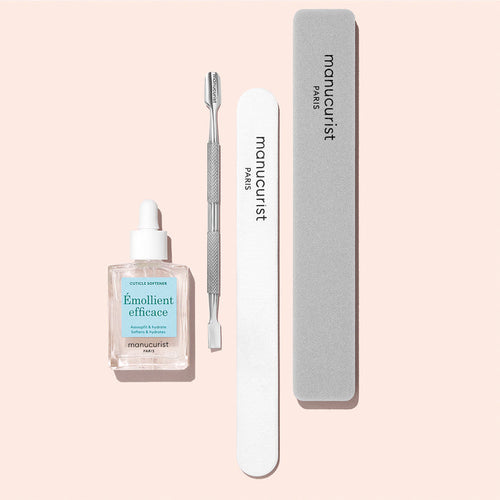 The Manucurist Nail Prep Set includes a cuticle remover, cuticle pusher, white emery board, and gray buffer—everything you need for nail care, beautifully arranged on a light pink background.