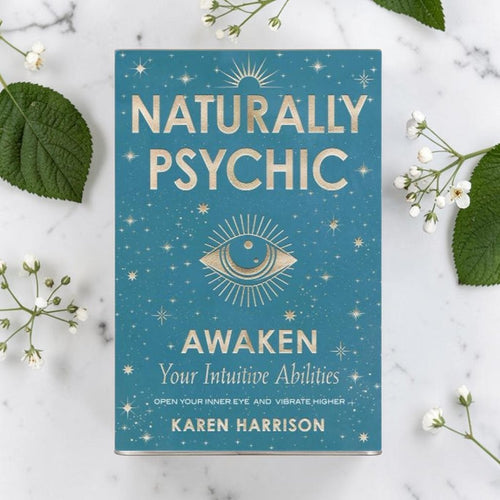 Book titled 'Naturally Psychic: Awaken Your Intuitive Abilities' by Karen Harrison on a marble surface with leaves and flowers.