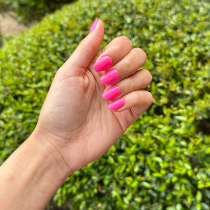 Neon Flamingo | Short | Round - Tab Press-On nails in vibrant neon pink with smooth glossy finish on natural hand outdoors