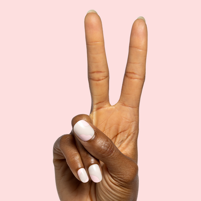 Organic Swirl | Extra Short | Round - Tab Press-On showing neutral short nails with soft pink swirl design on hand against pale pink background