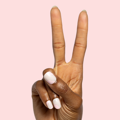 Organic Swirl | Extra Short | Round - Tab Press-On showing neutral short nails with soft pink swirl design on hand against pale pink background