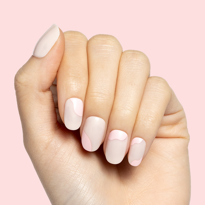 Organic Swirl | Extra Short | Round - Tab Press-On showing soft neutral nails with delicate light pink swirl design on hand against pale background