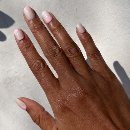 Organic Swirl | Extra Short | Round - Tab Press-On showing short neutral nails with soft pink swirl design on hand in natural light