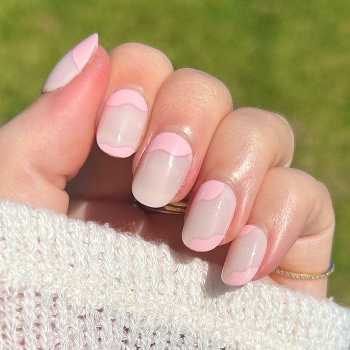 Organic Swirl | Extra Short | Round - Tab Press-On showing natural nails with soft pink wave design on hand outdoors in sunlight
