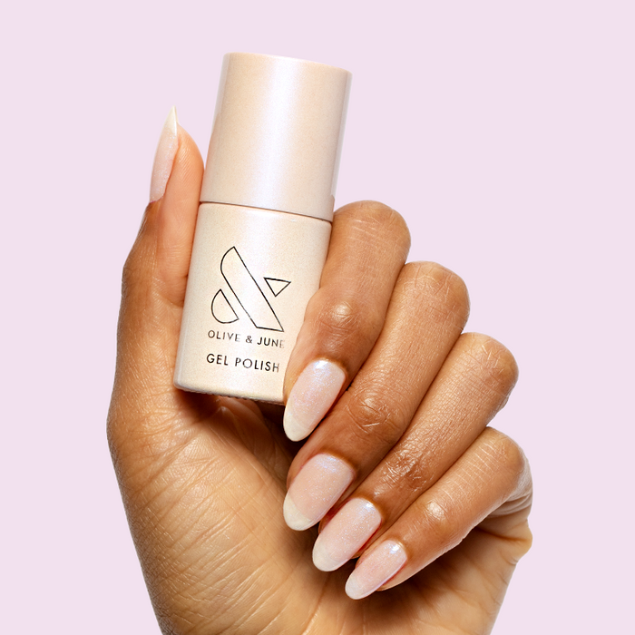 Pink Goldfish - Gel polish bottle held by hand with soft, shimmery pink iridescent nails for a delicate mani by Olive and June