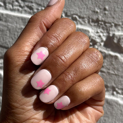 Pink Star Party | Extra Short | Round - Tab Press-On nails with soft pink base and bright pink star accents on hand outdoors