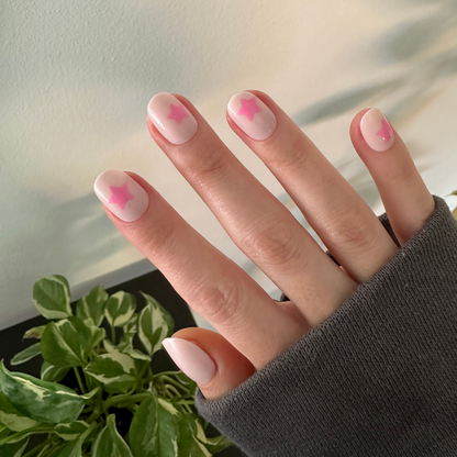 Pink Star Party | Extra Short | Round - Tab Press-On nails with soft pink base and translucent pink star accents on hand