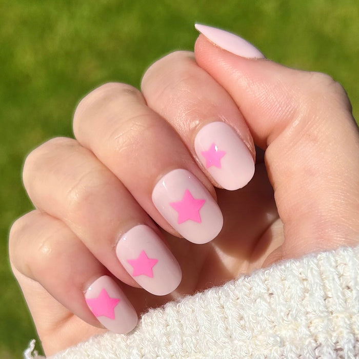 Pink Star Party | Extra Short | Round - Tab Press-On nails with soft pink base and bright pink star mani on hand outdoors
