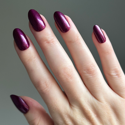 Plaza Shimmer | Medium | Oval - Tab Press-On nails in deep mulberry purple with sparkling finish on natural hand for at-home mani