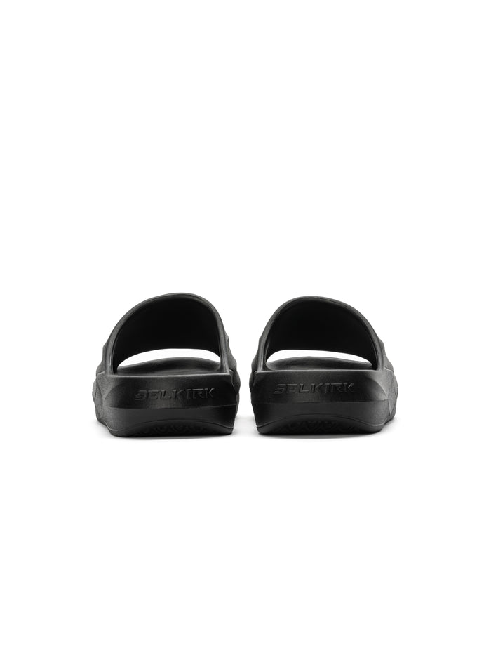 Black slide sandals shown from rear with embossed SELKIRK logo on heels