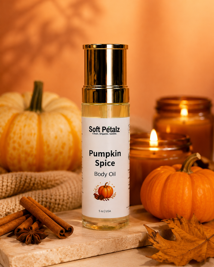 Bottle of Soft Pétalz Pumpkin Spice Body Oil with pumpkins, cinnamon sticks, and a candle in the background.