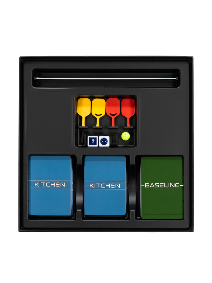 Game tray with two blue decks KITCHEN, green deck BASELINE, four yellow/red paddles, dice Z, and a green ball.
