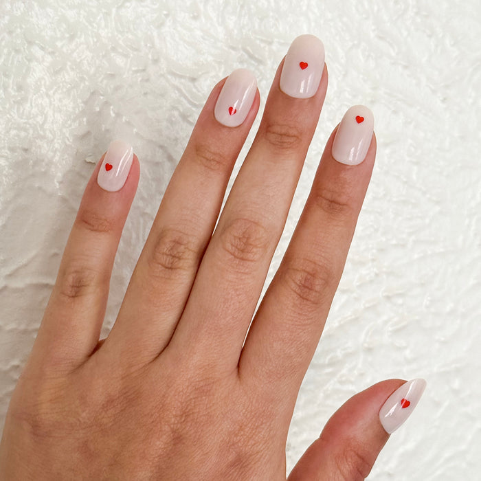 Hand with Red Hearts | Short | Round - Tab Press-On nails featuring neutral base and small red heart accent for a simple mani
