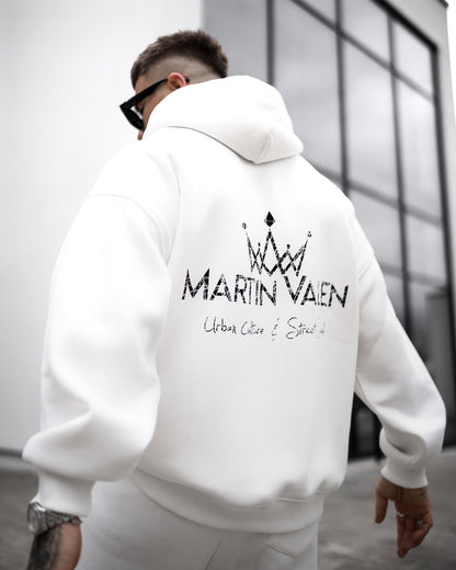 Martin Valen white tracksuit side view showing matching joggers and sneakers, small crown logo on thigh