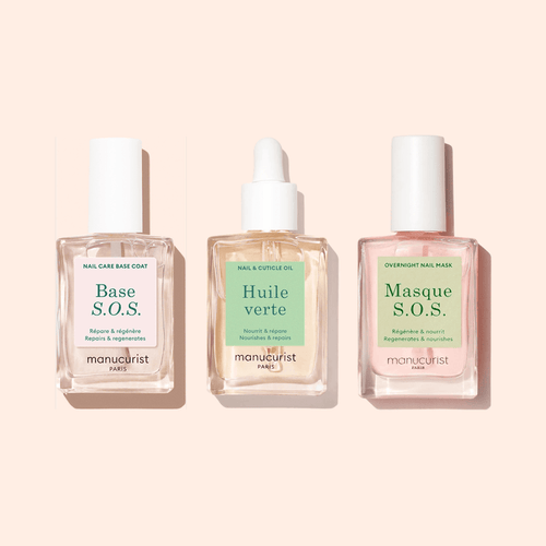 The Manucurist S.O.S Rescue Duo, displayed in clear glass bottles on a beige background, offers two targeted nail treatments—Base S.O.S. and Masque S.O.S.—designed to restore and strengthen damaged nails.