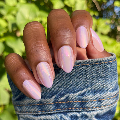 Hand with Rose Chrome - Press-On | Medium | Almond false nails in pink chrome mani outdoors with denim sleeve and green background