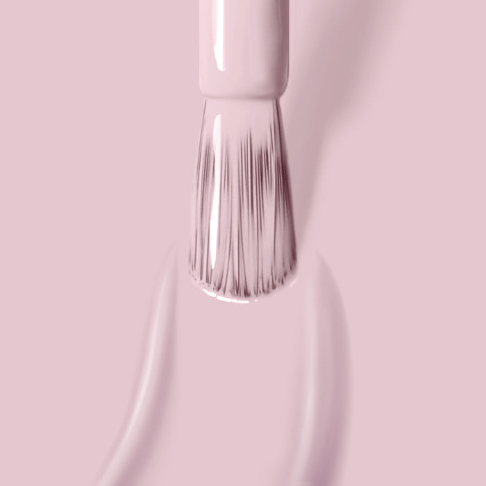 Close-up of a brush applying LONDONTOWN's Rosewater, a light pink, cruelty-free nail polish on a smooth surface. The bristles are visible, coated with the high-shine formula.