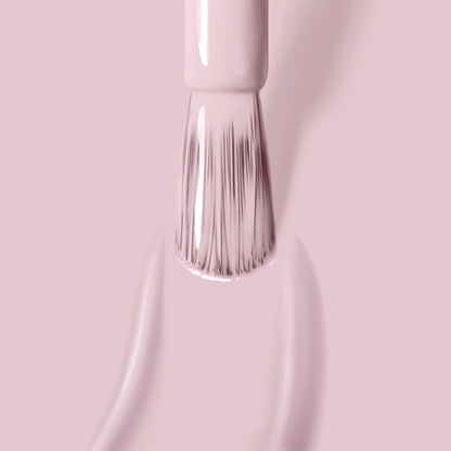 Close-up of a brush applying LONDONTOWN's Rosewater, a light pink, cruelty-free nail polish on a smooth surface. The bristles are visible, coated with the high-shine formula.