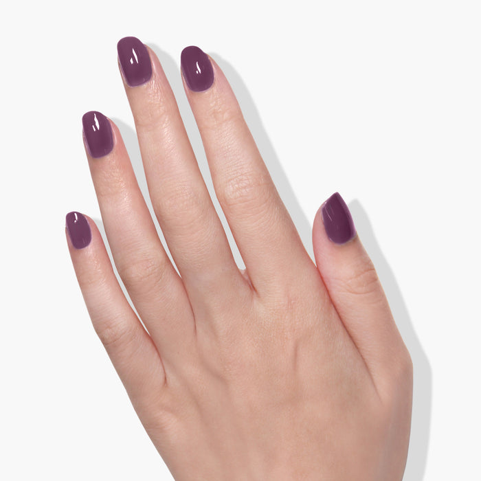 A hand with neatly manicured nails painted in LONDONTOWN's dark purple vegan shade "Save the Queen" against a white background.